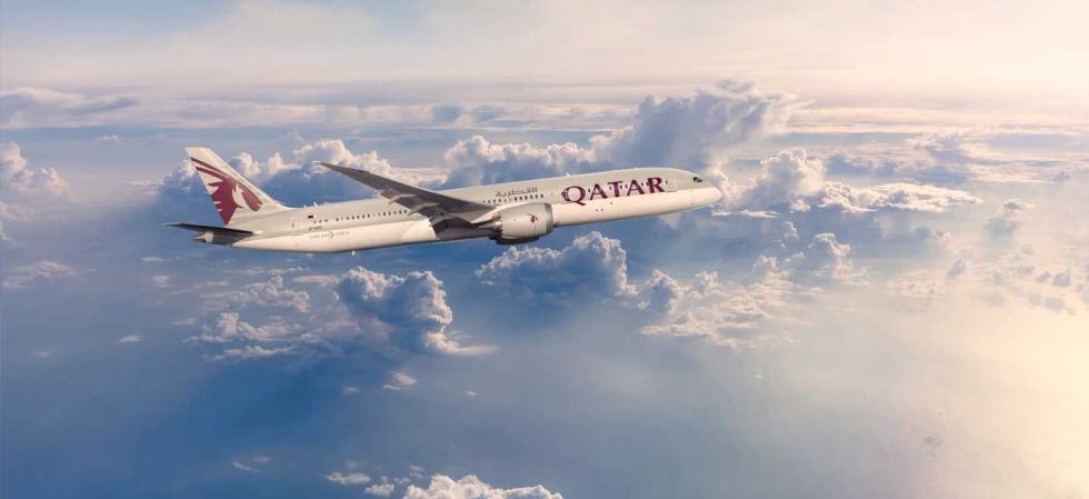 A Qatar Airways aeroplane in a blue sky with clouds